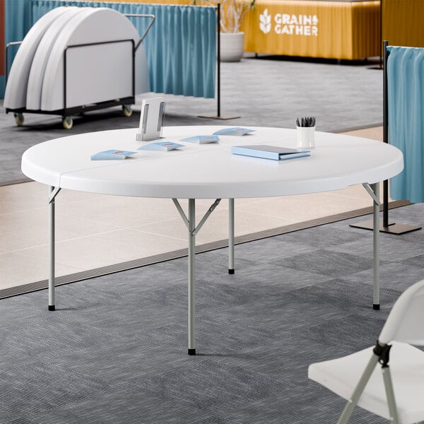 A 72-inch round granite white plastic bi-folding table with gray legs.
