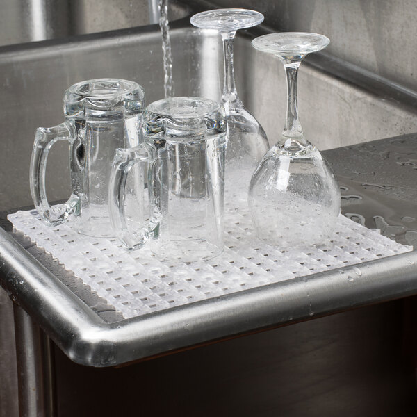 Clear interlocking bar mats on a metal surface with glasses on it.