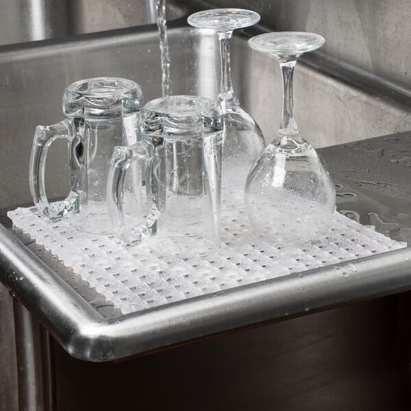 A clear interlocking bar mat on a metal surface with clear glasses on it.