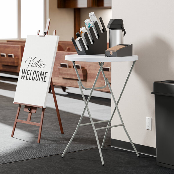 A round, granite white, heavy-duty plastic folding table with gray legs at bar height.