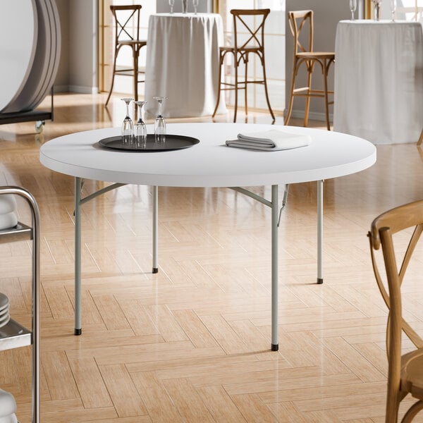 A 60-inch round heavy-duty granite white plastic folding table with gray legs.