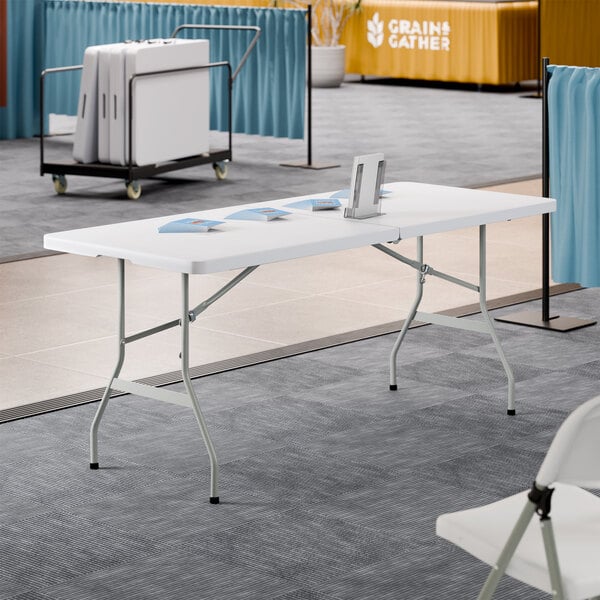 A 30-inch by 72-inch granite white plastic bi-folding table with gray metal legs.