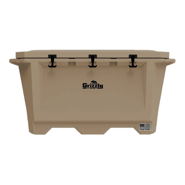 A tan Grizzly Cooler with black handles on a table outdoors.