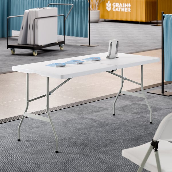 A rectangular granite white plastic bi-folding table with gray metal legs.