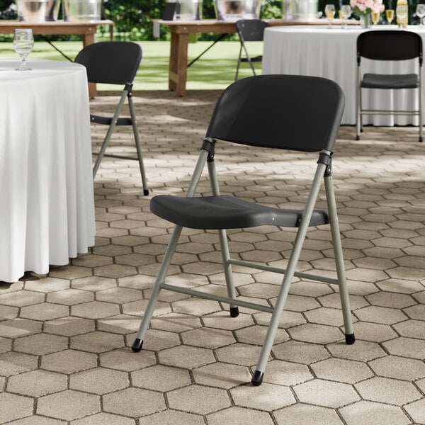 A black contoured injection-molded folding chair with a charcoal frame and gray legs.
