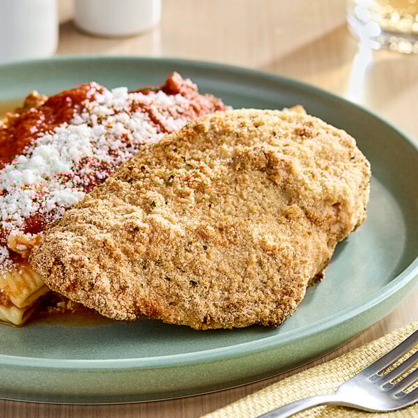 A plate of food with chicken and sauce topped with Imperia Italian-Style Seasoned Bread Crumbs on a wood table.