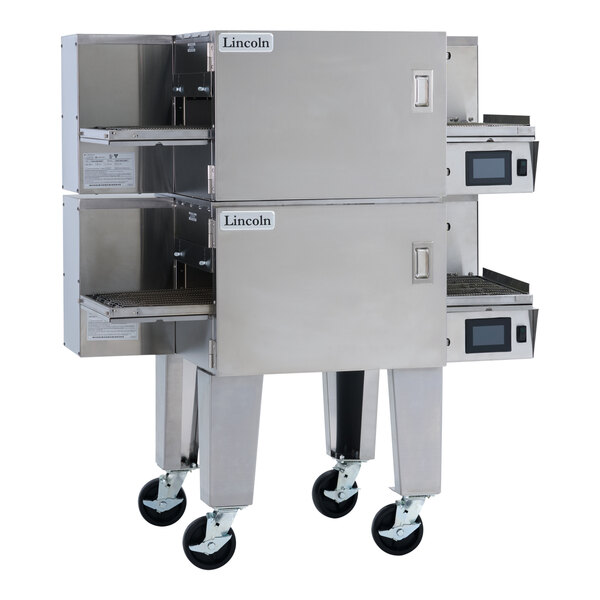 A double stacked stainless steel electric conveyor oven with two wide belts and digital controls, mounted on caster wheels.