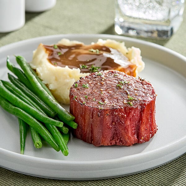 A plate with a Juicy Marbles plant-based vegan filet, green beans, and mashed potatoes with gravy.