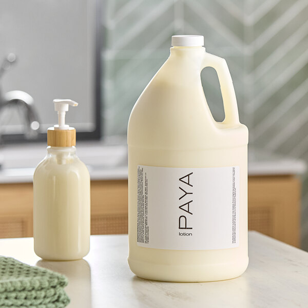 A white bottle of PAYA papaya lotion on a counter next to a white bottle of liquid.