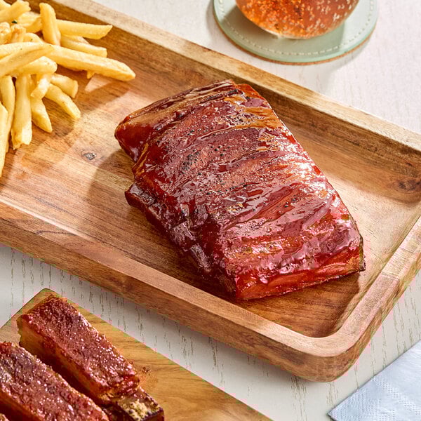A serving of plant-based vegan bone-in baby ribs with a side of French fries on a wooden tray.