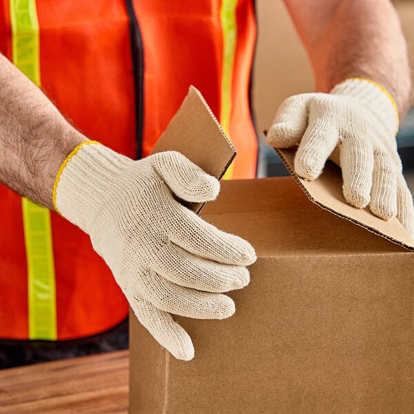 A person wearing Lavex work gloves holding a cardboard box.