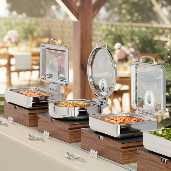 An outdoor buffet table with Acopa Manchester chafing dishes of food.