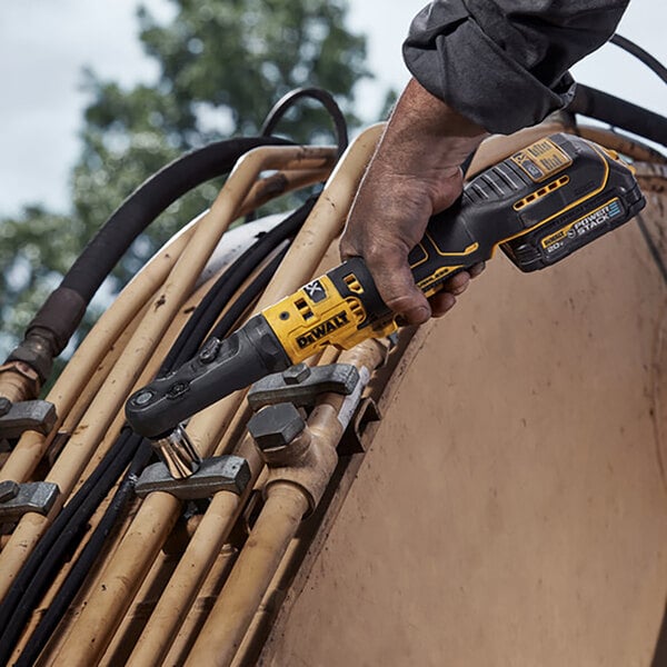 A hand holding a yellow and black DCF510B power tool.