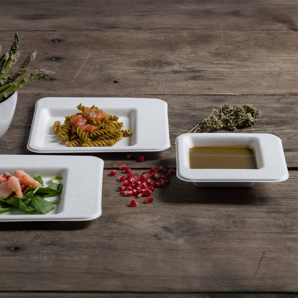 A table with three Jungle Diamond compostable sugarcane pulp plates of pasta with tomatoes on top.