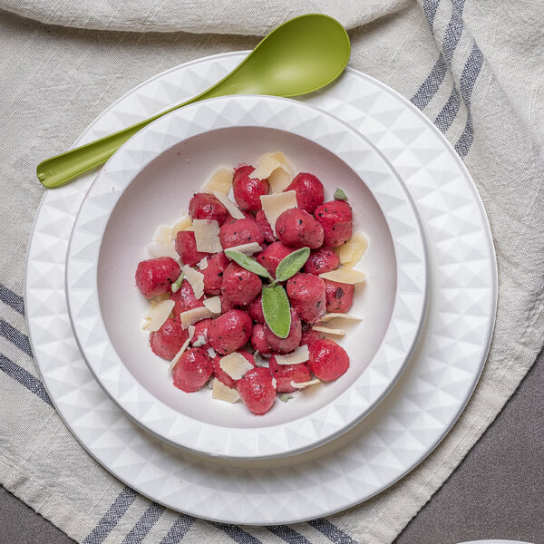 A white Jungle Decor compostable sugarcane pulp bowl filled with food and a spoon.
