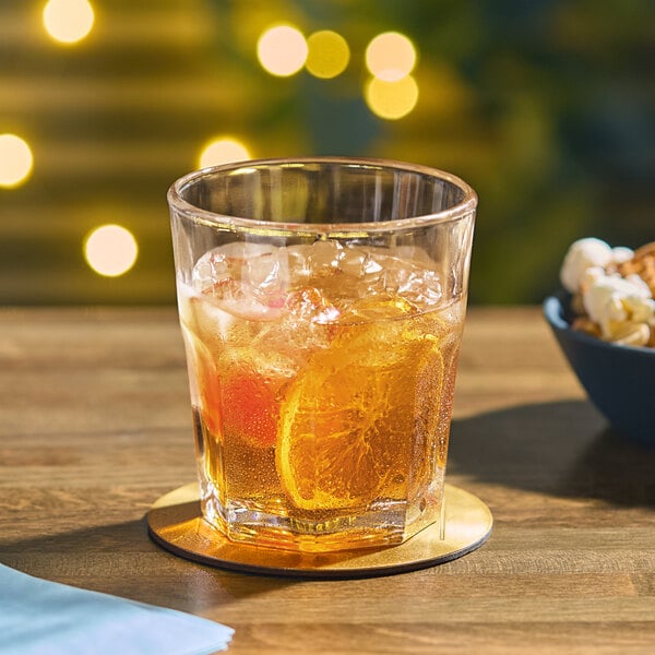An Acopa Memphis rocks glass filled with ice and orange juice on a table with a bowl of popcorn.