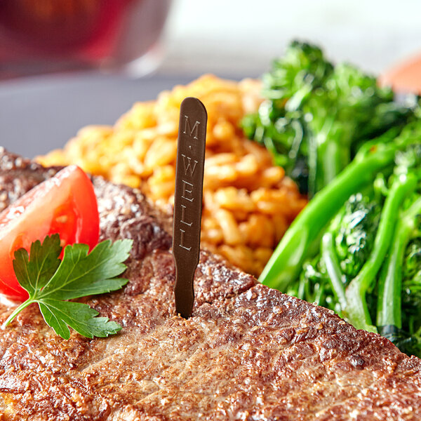 A steak with Royal Paper brown medium well steak marker and vegetables on a plate.