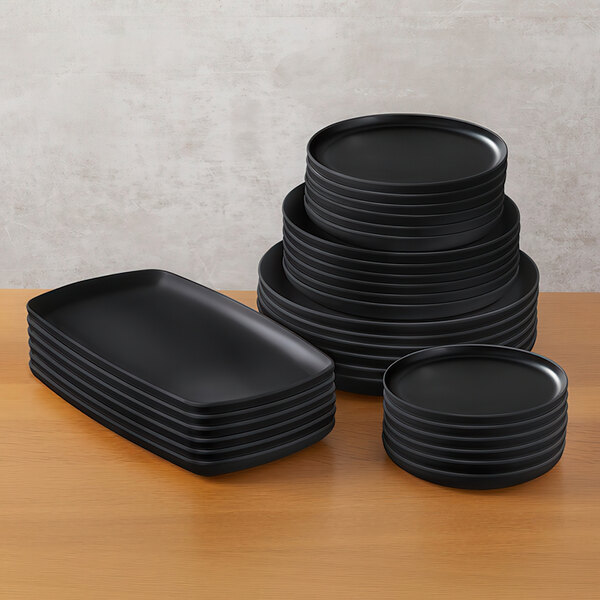 A stack of American Metalcraft black rectangle melamine platters on a table.