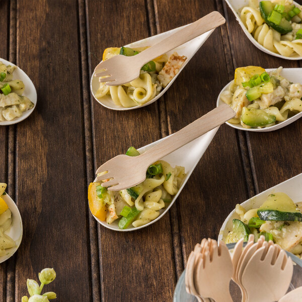 Eco-gecko wooden taster forks in a bowl of pasta with vegetables.