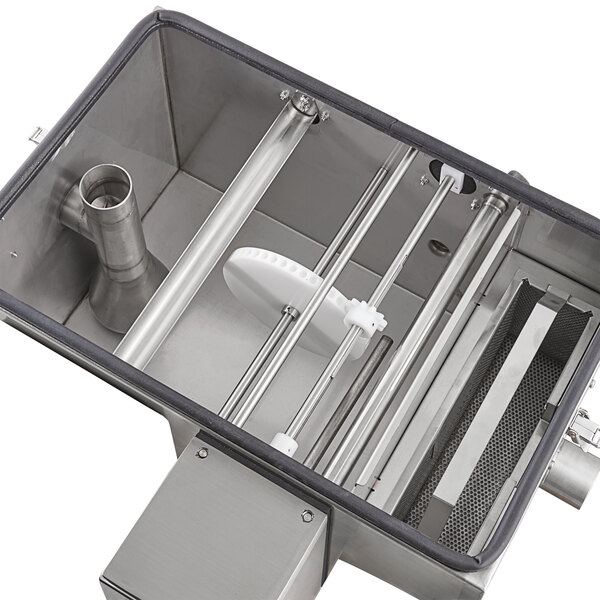A Grease Guardian automatic grease trap with stainless steel and white plastic parts and metal rods inside.