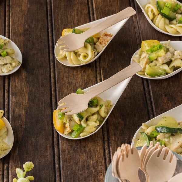 Eco-gecko wooden taster forks in a bowl of pasta with vegetables.