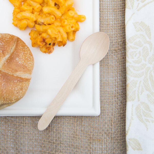 A wooden spoon on a plate of macaroni and cheese.