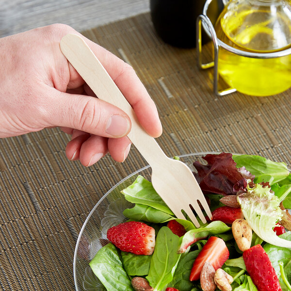 A person holding an Eco-gecko wooden fork over a salad.