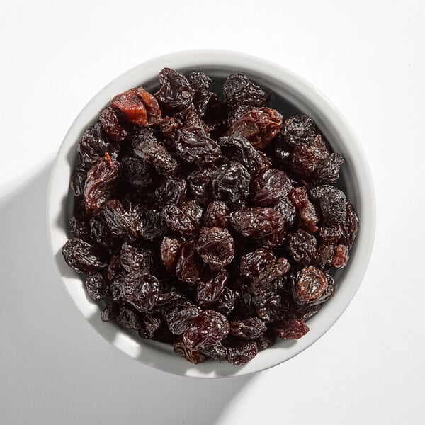 A white bowl filled with dried flame raisins.