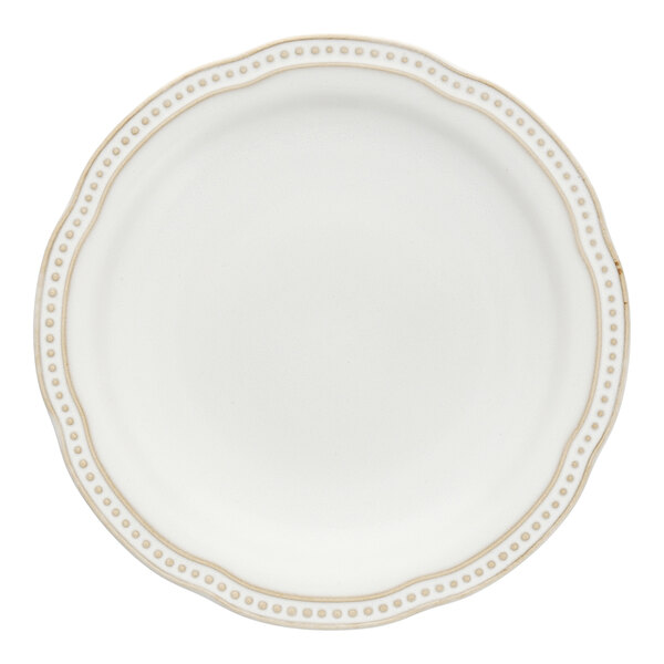 A close up of a white Mannette Perls stoneware salad plate with a scalloped edge and embossed pearl design.