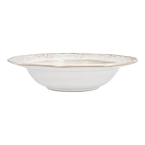 A white stoneware soup bowl with a scalloped and embossed floral edge.
