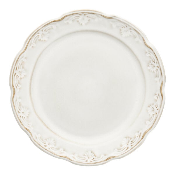 A close up of a Mannette Floral by Fortessa white stoneware dinner plate with a scalloped and floral edge and gold trim.