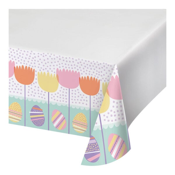 A white tablecloth with a pattern of colorful eggs and tulips.