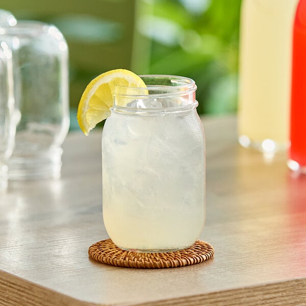 A glass jar of Sunkist Lemonade with a drink in it on a table.