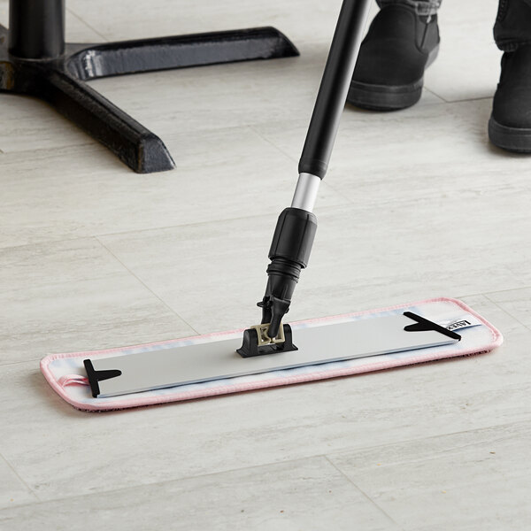 A person using a Lavex pink microfiber mop to clean a white floor.