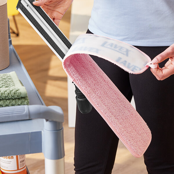 A woman using a pink Lavex microfiber mop pad.