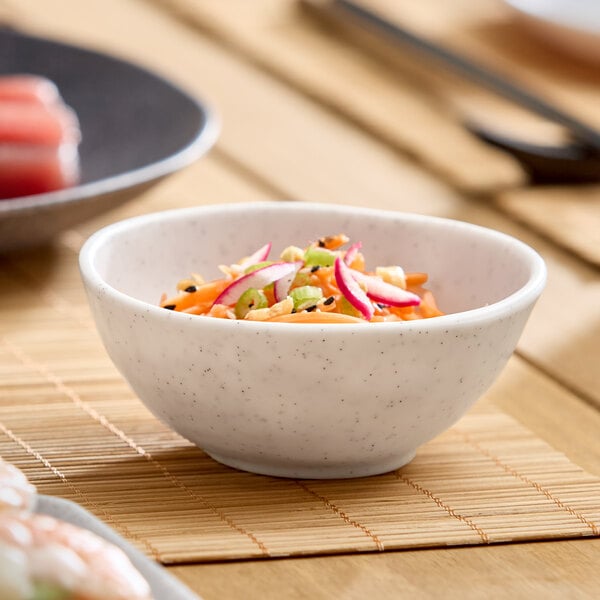 A small white round melamine bowl filled with a colorful salad.