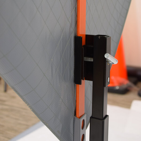 A close-up of a hitch mount stand holding a roll-up sign with a reflective surface.