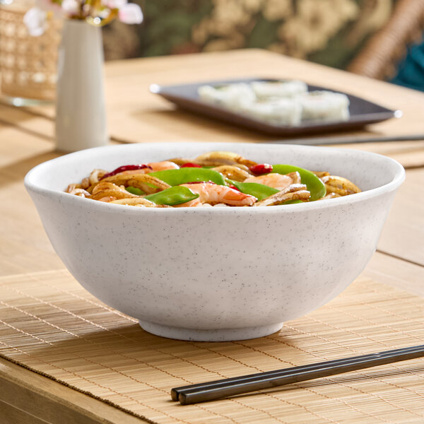 A large white round melamine bowl filled with food, placed on a table.