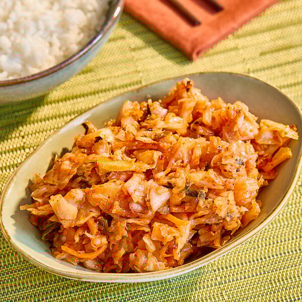 A bowl of chopped, fermented kimchi with a reddish hue, served as a side dish.