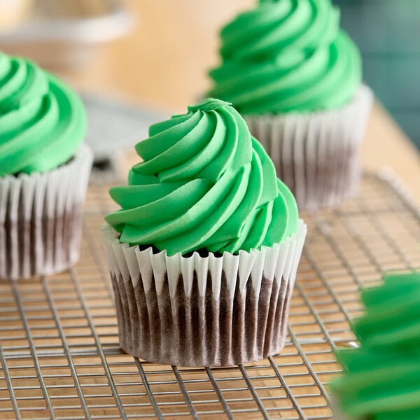 A chocolate cupcake with green frosting on top, displayed on a cooling rack.