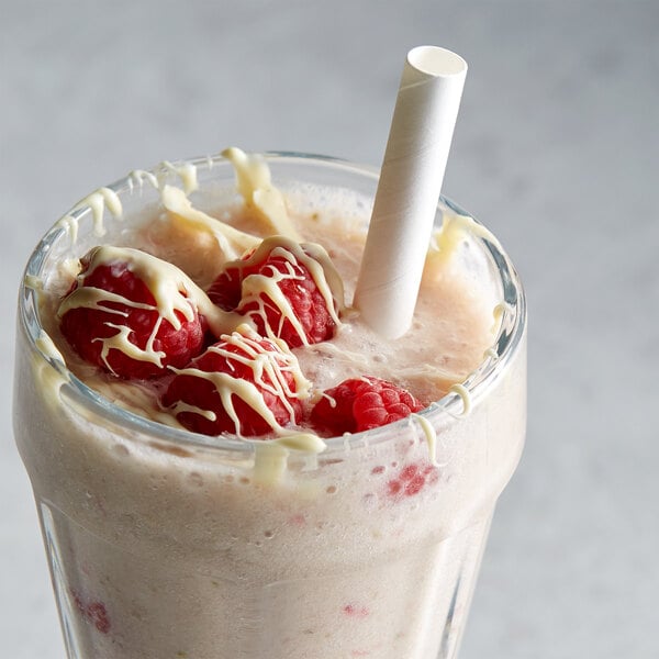 A glass of milkshake with a straw and raspberries made with DaVinci Gourmet Sugar-Free White Chocolate Flavoring Syrup.