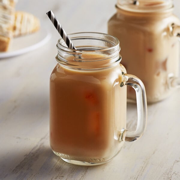 Two glass mugs filled with coffee and cream with DaVinci Gourmet French Vanilla syrup on the side.