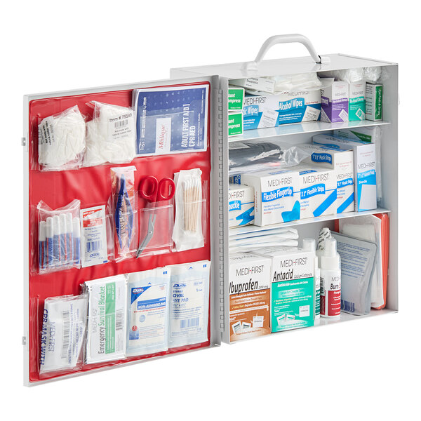 A red and white Medique first aid kit cabinet with many medical supplies inside.