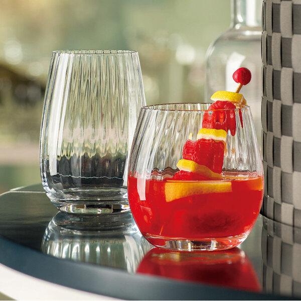 Two Arcoroc stemless wine glasses filled with red cocktails and lemon wedges on a table.