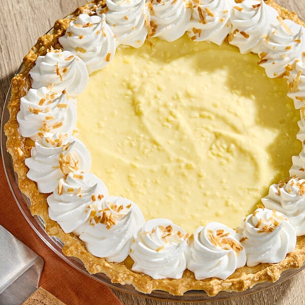 A coconut cream pie with a creamy yellow filling, topped with whipped cream and toasted coconut flakes around the edge.