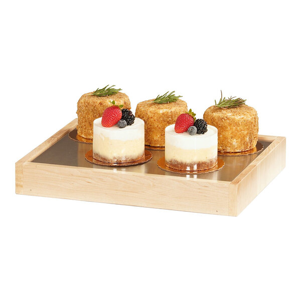 A Cal-Mil blonde maple wood cold housing frame with a gel-filled cold platter holding three desserts with fruit on top.