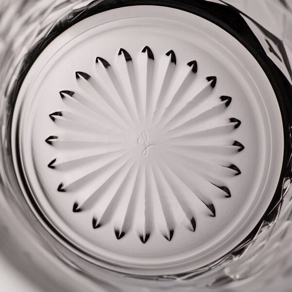 A close-up view of the bottom of a clear Libbey Ocular 8 oz. rocks or old fashioned glass with a decorative starburst pattern.