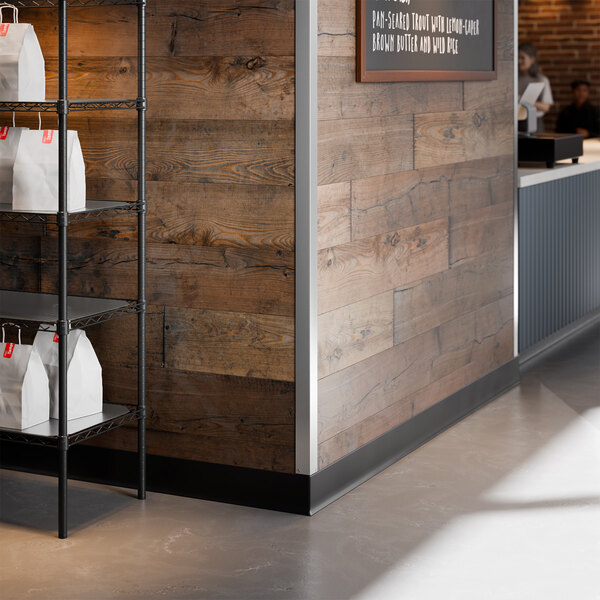 A stainless steel wall corner guard with mounting holes installed on the corner of a wooden wall.