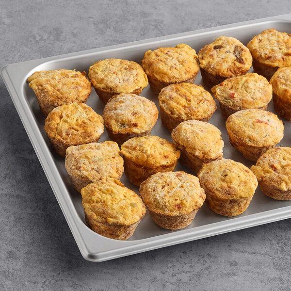 A baking tray filled with multiple bacon, cheese, pepper, and hashbrown egg bites.