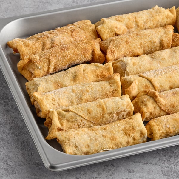 A tray of golden-brown taco log egg rolls arranged in rows.